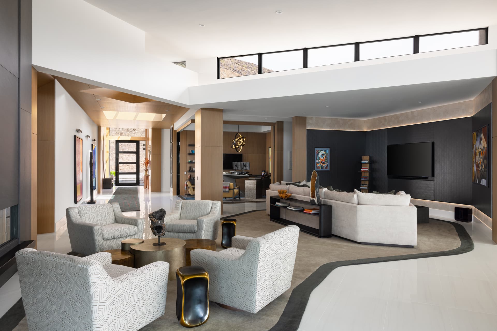 Open living room with patterned swivel chairs and gallery-lit art wall