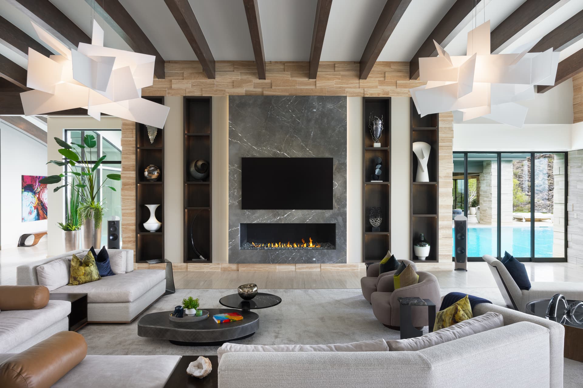 Great room with marble fireplace wall, twin sculptural pendants, and pool view